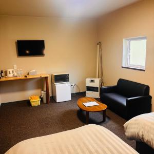a hotel room with a couch and a tv at ホテル　ロマン in Koshimizu-shigai
