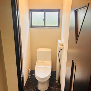 a small bathroom with a toilet with a window at ホテル　ロマン in Koshimizu-shigai