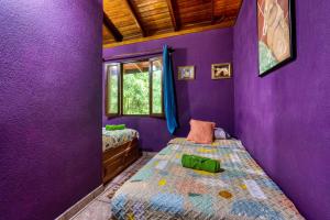 a purple room with two beds and a window at Casa Selva in Dominicalito