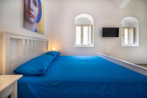 a blue bed in a room with two windows at Demetra in Noto