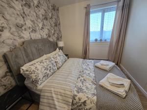 a bedroom with a bed and a window with towels at Relax Stay 2 Bedroom in Theale