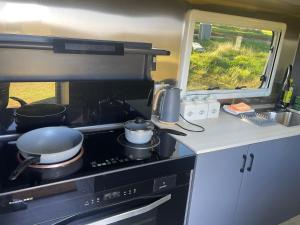 a kitchen with a stove with pots and pans on it at One Life Glamping Caravan Rawson in Rawson