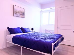 una camera da letto con un letto con lenzuola blu e una finestra di Condo in Secord a Edmonton