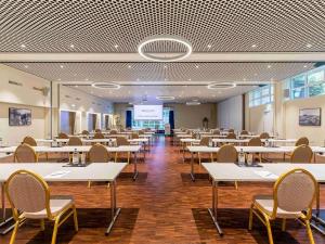 a large room with tables and chairs and a presentation at Mercure Lenzburg Krone in Lenzburg