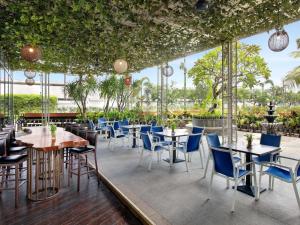 a restaurant with tables and chairs and plants at Novotel Samator Surabaya Timur in Surabaya