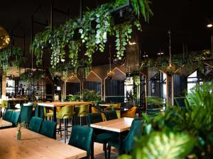 a restaurant with wooden tables and chairs and plants at ibis styles Grudziadz in Grudziądz