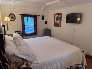 a bedroom with a white bed and a television at Enchanted Fox Dell Cottage in Monticello
