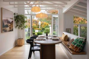 a dining room with a table and chairs and windows at Wondervale in Burrawang +12 photos