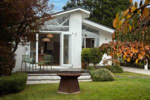 a small white house with a bench in the yard at Wondervale in Burrawang