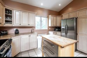 a kitchen with white cabinets and a stainless steel refrigerator at Le Chaleureux du Lac Blanc - Nominingue in Nominingue