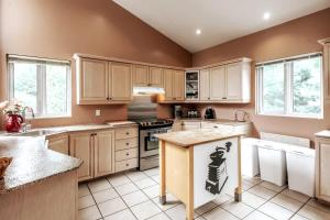 a kitchen with white appliances and brown walls and windows at Le Chaleureux du Lac Blanc - Nominingue in Nominingue