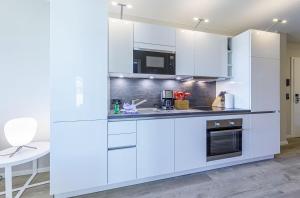 a white kitchen with white cabinets and a table at Großer Strandkorb - Stilvolles Ferienapartment in der Alten Seefahrtsschule in Wustrow