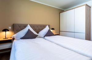 a bedroom with a large bed with white sheets and pillows at Apartment Frau Hummel - Urlaub am Krakower See in Krakow am See