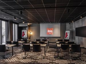 a lecture room with tables and chairs and a projection screen at ibis Le Mans Centre Gare Nord in Le Mans
