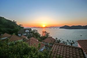 a sunset over the water with houses and roofs at namhe acro pension in Namhae