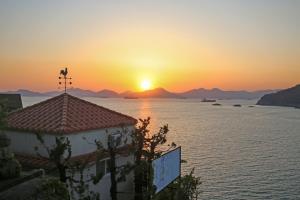 a sunset over the water with a building in the foreground at namhe acro pension in Namhae