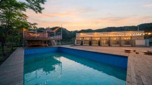 a house with a swimming pool in front of a building at GaPyeong Yeoldudal Spapension&Camping in Gapyeong