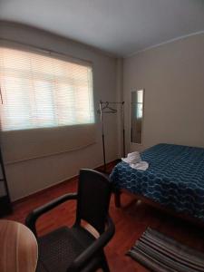 a bedroom with a bed and a chair and a window at Alójate Huánuco in Huánuco