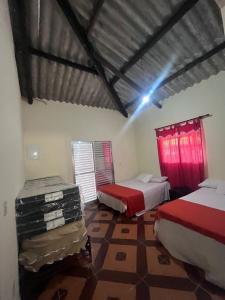 two beds in a room with red curtains at Sítio Santo Expedito in Salesópolis