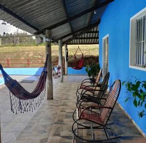 a patio with hammocks and a blue house at Sítio Santo Expedito in Salesópolis