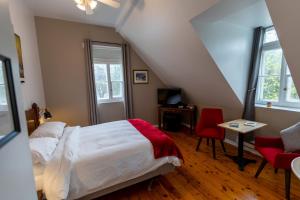 a bedroom with a bed and a desk and two chairs at Aux petits oiseaux in Baie-Saint-Paul