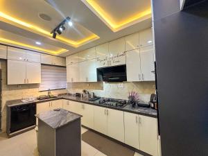 a kitchen with white cabinets and a black appliances at Engeemos Bookastay Apartments in Abeokuta