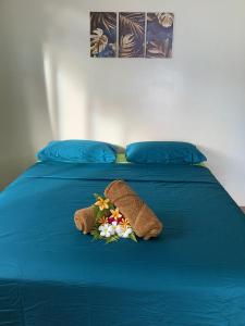 a blue bed with two stuffed animals and flowers on it at Sarahlodge in Tahaa