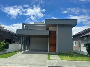 a modern house with a pivot door in a yard at Casa Cerejeiras - Condomínio Privado in Bananeiras