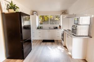 a kitchen with white cabinets and a black refrigerator at Ovens River Retreat in Harrietville +2 photos