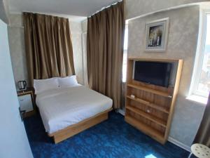 a hotel room with a bed and a television at Gandan Peace Guest House in Ulaanbaatar