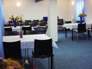 a dining room with white tables and black chairs at Gaestehaus Rehbein in Calbe