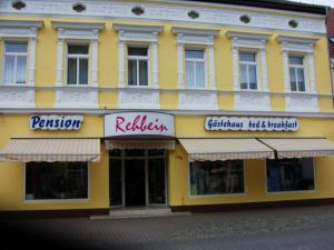 Gaestehaus Rehbein في Calbe: مبنى أصفر عليه لافتات