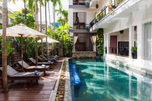 a pool with chairs and umbrellas next to a building at SAKABAN Suite in Siem Reap