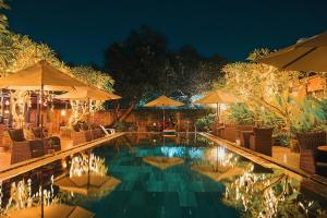 a swimming pool with chairs and umbrellas at night at B'Hoian Retreat in Hoi An