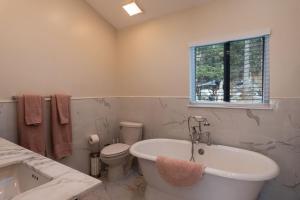a bathroom with a tub and a toilet and a window at Sun Drenched Lakefront Cove in Monticello +29 photos