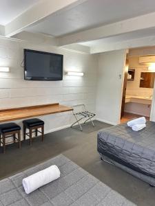 a room with two beds and a tv on a wall at Charles Sturt Motor Inn in West Wyalong