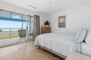 a bedroom with a bed and a balcony at Villa 3 Beach Front Tangalooma in Tangalooma