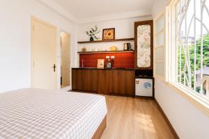 a bedroom with a bed and a kitchen with a window at Anchie Maison Hà Nội in Hanoi
