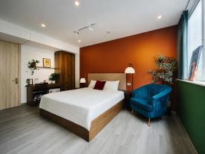 a bedroom with a bed and a blue chair at Anchie Maison Hà Nội in Hanoi