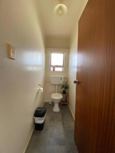 a small bathroom with a toilet and a window at Waitangi Beach House in Paihia +18 photos
