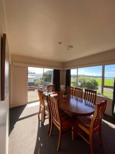 a dining room with a wooden table and chairs at Waitangi Beach House in Paihia