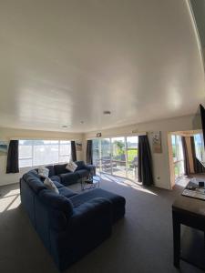 a living room with a blue couch and a large window at Waitangi Beach House in Paihia