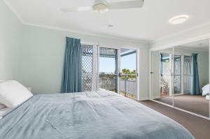 a bedroom with a large bed and a balcony at Villa 30 Tangalooma in Tangalooma