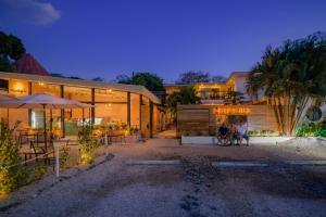 a group of people sitting in front of a building at Hostel La Botella de Leche - Tamarindo in Tamarindo