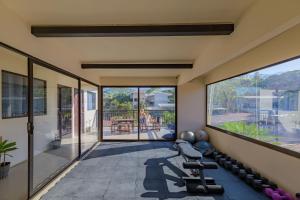 an empty house with a gym with large windows at Hostel La Botella de Leche - Tamarindo in Tamarindo