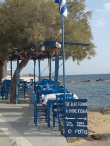 un gruppo di tavoli e sedie blu sulla spiaggia di O Fotis ad Agios Prokopios