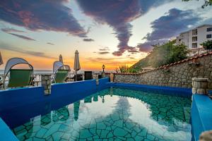 a swimming pool with a sunset in the background at Vila Dora in Dobra Voda