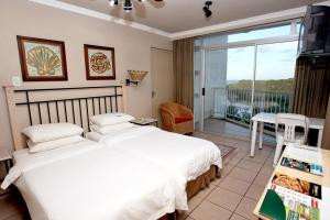 a bedroom with two beds and a balcony at The Reef Apartments in East London