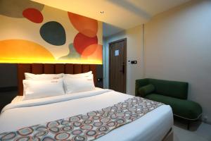 a bedroom with a large bed and a green chair at TheCloud Hotel in Nizāmābād