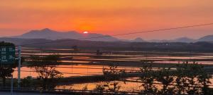 a sunset over a body of water with mountains at Paju Seolreda in Paju